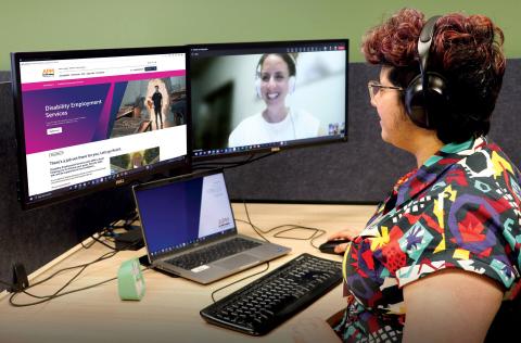A person in a colorful shirt using a laptop and connected to someone on a video call. 