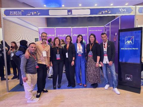 Seven people smiling for a photo with a large blue screen next to them.